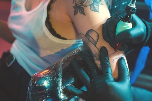 A tattoo artist outlining a shoulder piece